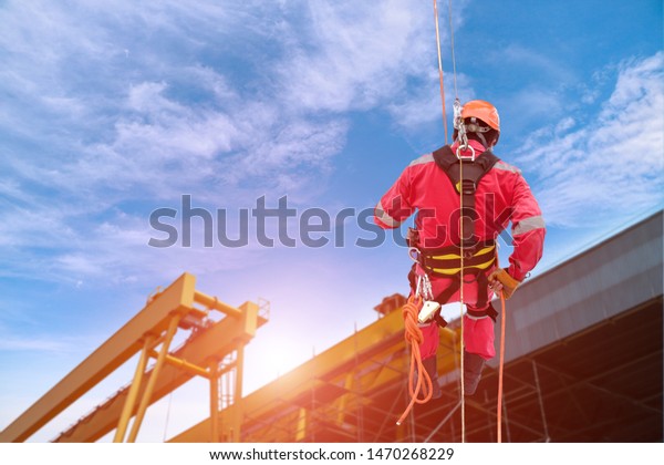 rope access, Construction worker wearing safety\
harness, Safety, Worker Demonstration the Abseiling of high wear\
equipment protective PPE.