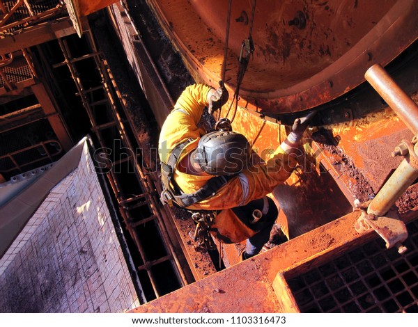 Rope access industrial technician miner fitters,\
boilermaker wearing fully safety harness, abseiling working\
maintenance inspecting cleaning chute roller isolated mining iron\
ore construction Perth