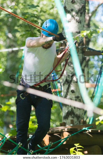 Rope adventure - man about to walk\
on the suspension rope bridge attached to the\
tree