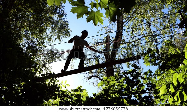 Rope adventure - man walk on the suspension rope\
bridge attached to the\
tree