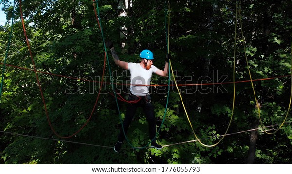 Rope adventure - man walk on the suspension rope\
attached to the tree
