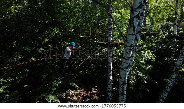 Rope\
adventure - man walking on the rope between\
trees