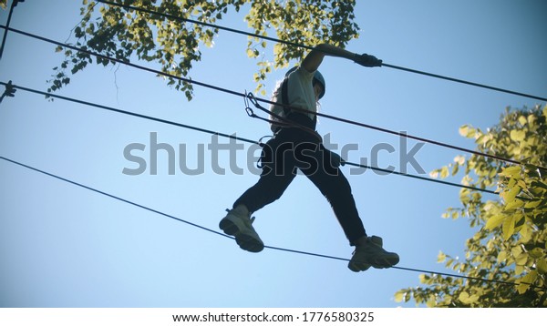 Rope adventure - slim woman walks on the\
suspension rope bridge