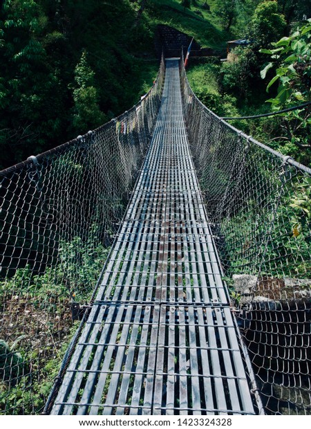 Rope bridge for crossing river in Nepal during trek\
to Annapurna Base Camp.