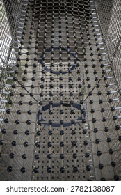 Rope bridge on the upper level with rings on the first level of a rope castle playground structure.