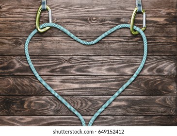 Rope For Climbing Sport In Shape Of A Heart With Carbines On Wooden Background, Top View. Copy-space.