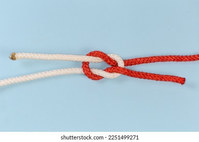 Rope grief knot, similar to reef knot, but impractical and used as device for trick, view on a blue background - Shutterstock ID 2251499271