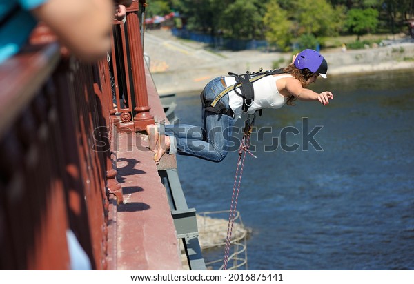 Rope jumping. Girl in a helmet jumping from\
a bridge. August 20, 2012. Kiev,\
Ukraine