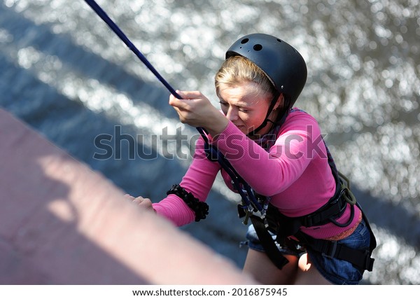 Rope jumping. Girl in a\
helmet climbing on a bridge after jumping. August 20, 2012. Kiev,\
Ukraine