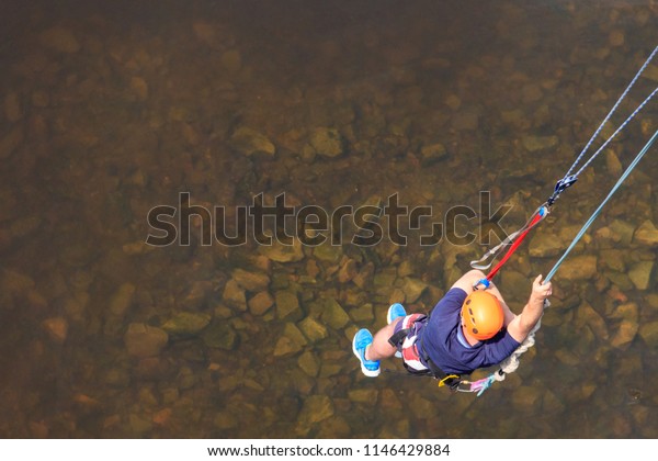 Rope jumping from\
high altitude of bridge. Bungee jumping from pedestrian bridge over\
beautiful river