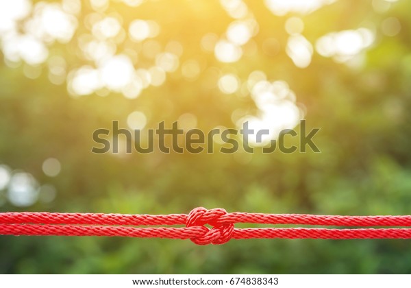 Rope knot\
 , red string knotted on nature\
background