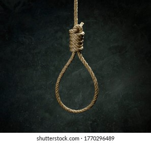 Rope noose for hangman made of natural fiber rope on a grainy gray wall. Hemp rope knot for gallows and Hang man over black concrete wall. Hang rope noose for homicide or commit suicide concept.