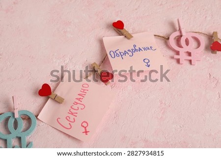 Rope and paper sheets with written text in Russian language on pink grunge. Sexual education