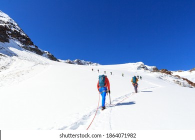 Rope Team Mountaineering With Crampons On Glacier Sexegertenferner Towards Sexegertenspitze And Mountain Snow Panorama With Blue Sky In Tyrol Alps, Austria