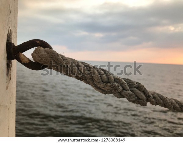 The rope tied on the bridge. And the sun sets\
off the horizon.