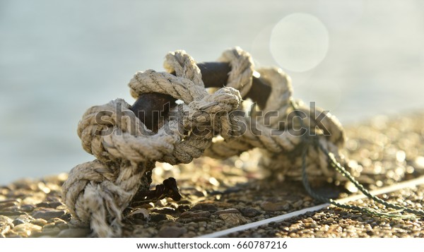 The rope tied to the steel harbor ring on the\
bridge and reflective water.\
