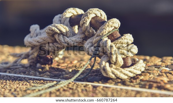 The rope tied to the steel harbor ring on the\
bridge and reflective water. Fair yellow gold Make art The back is\
a bokeh blur.