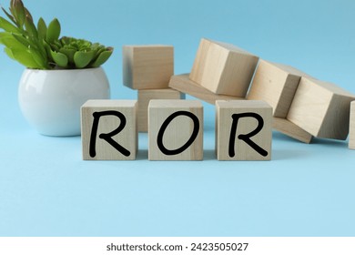 ROR - Rate Of Return blue background and different wooden blocks and plants in a pot. text on wooden blocks