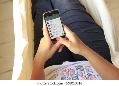 ROSARIO, ARGENTINA - JANUARY 11, 2017: Top View A Woman In A Hammock With A Smartphone And Whatsapp´s Contact List On Screen. Young Woman. Millennial. Communications. Application.