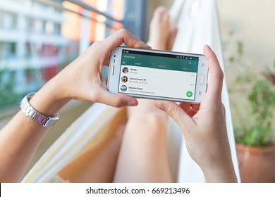 ROSARIO, ARGENTINA - JANUARY 19, 2017: Girl In A Hammock With A Smartphone In Her Hands And Whatsapp´s Contact List On Screen. Young Woman, Millennial Using Whats App Messenger.