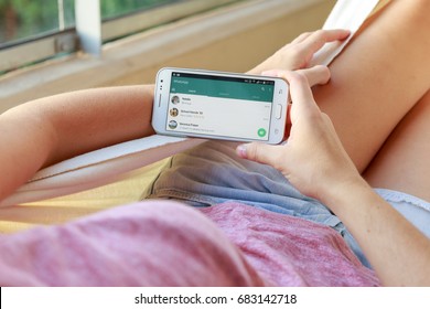 ROSARIO, ARGENTINA - JANUARY 19, 2017: Girl In A Hammock With A Smartphone In Her Hands And Whatsapp´s Contact List On Screen. Young Woman, Millennial Using Whats App Messenger.