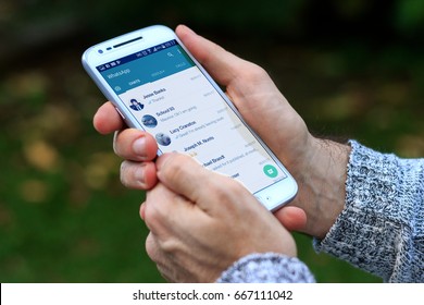 ROSARIO, ARGENTINA - JUNE 18, 2017: Man With A White Cell Phone In His Hands. On The Screen You Can See The Whatsapp Application With The Contact List Open. 