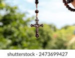 Rosary hanging in the air with a blurred outdoor background on a sunny day