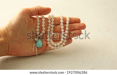 Rosary mala 108 beads from natural stones Moonstone lie in girl's hand. Author's jewelry from natural stones, Buddhism, matra, prayer, rosary from stones for prayer and beauty. Rosary in hand.