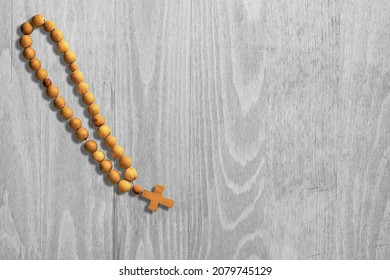 A rosary on  wood background with Christian cross