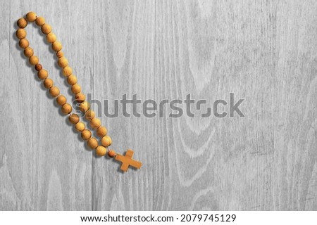 A rosary on  wood background with Christian cross