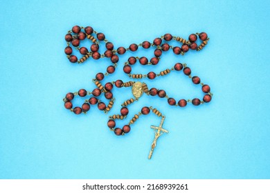 Rosary wooden beads and crucifix christian cross on blue background. Catholic symbol. Flatlay, top view, lay out, isolated. Pray for God, faith in Jesus Christ and believe religion concept. Closeup
