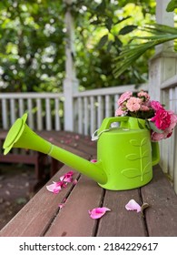 Rose Arranged In A Green Watering Pot Putting On A Wooden Bench Top In A Gazebo