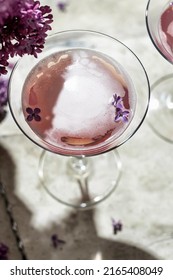 Rose Champagne Glass With Lilac Flowers And Shadow On Gray Background, Close Up, Space For Text. Summer Drink For Party Or Vine Shop Or Tasting Concept