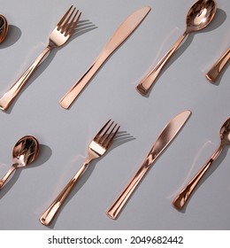 Rose Gold Dinnerware Cutlery Utensils, Forks Knives, Spoons on Gray Background