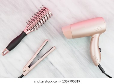 Rose gold hair styling products on marble countertop