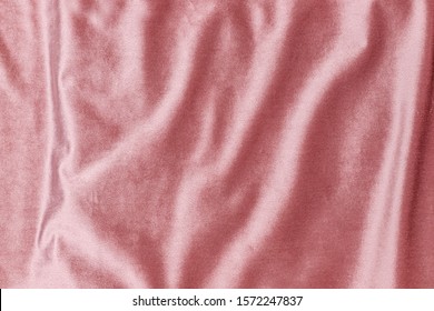 Rose gold pink glamour velvet background. Velour flannel texture. Shiny draped wrinkled luxurious cloth. Soft rose plush fabric with drapery. Smooth elegant pink silk velvet or satin texture