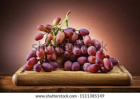 rose grape on wooden cutting board and brown gradient background
