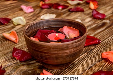 Rose petals and burning candles in water on wooden background - Powered by Shutterstock