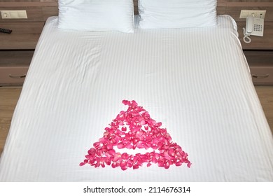 Rose Petals In The Form Of A Drawing Lie On A White Bed In The Hotel. Poor Service, A Bad Joke On The Customer.