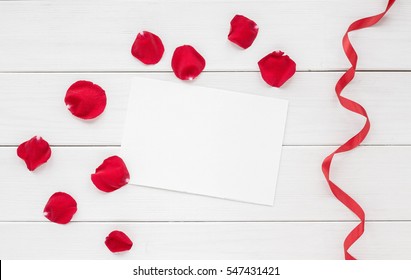 Rose petals, red ribbon and empty paper on white wooden background. Flat lay, top view. - Powered by Shutterstock