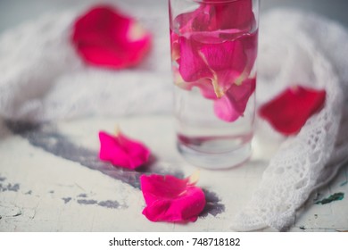 Rose pink water - water with petals of rose flowers in a transparent glass