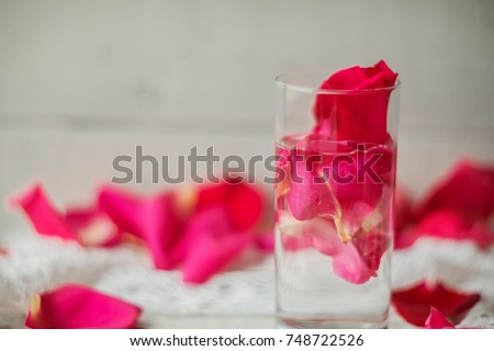 Rose pink water - water with petals of rose flowers in a transparent glass.