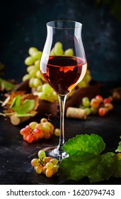 Rose pink wine glass at wine tasting concept. Gray background with grape and leaves. Copy space