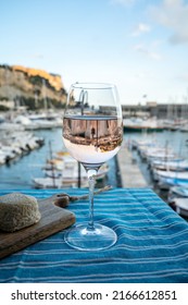 Rose Provencal wine in glass served with goat cheeses on outdoor terrace with view on old fisherman's harbour with colourful boats in Cassis, Provence, France