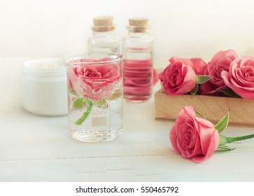 Rose scent holistic cosmetic. Fresh pink blossom, array of glass vials and apothecary bottles. Flower Aromatherapy. Soft light and focus