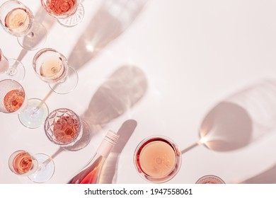 Rose wine assortment in crystal glasses, bottle of rose champagne sparkling wine with daylight and shadows. Summer alcoholic drink top view, winetasting concept.