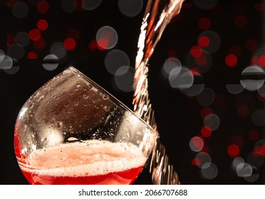Rose wine falling in a way splashing into a wine glass, on a black background