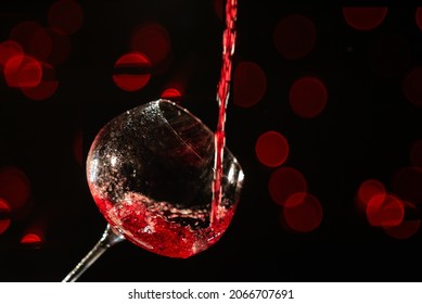 Rose wine falling in a way splashing into a wine glass, on a black background
