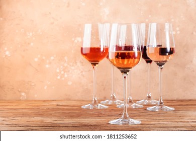 Rose wine glasses assortment on wine tasting. Degustation different varieties, colors and shades of pink wine concept. Beige background
