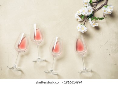 Rose Wine In Glasses And Blossom Sakura Branch Artificial. Beige Concrete Background. Top View, Flat Lay. Spring Holidays Concept.